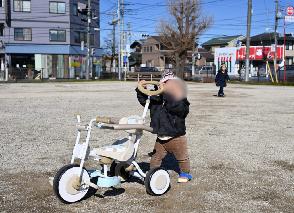 公園にいる三輪車と1歳児
